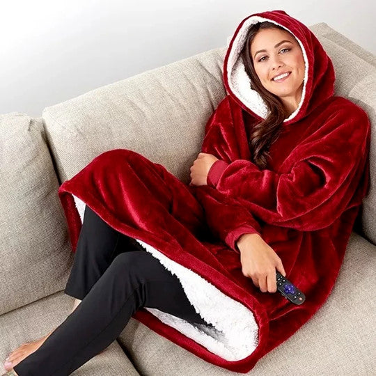 Persoon draagt een rode Sherpa Fleece XXL hoodie, ontspannen op de bank.