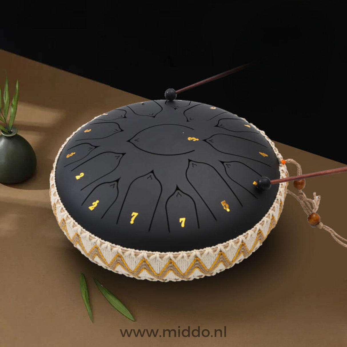 Handen bespelen een zwarte Harmonii KlankOase Steel Tongue Drum met mallets