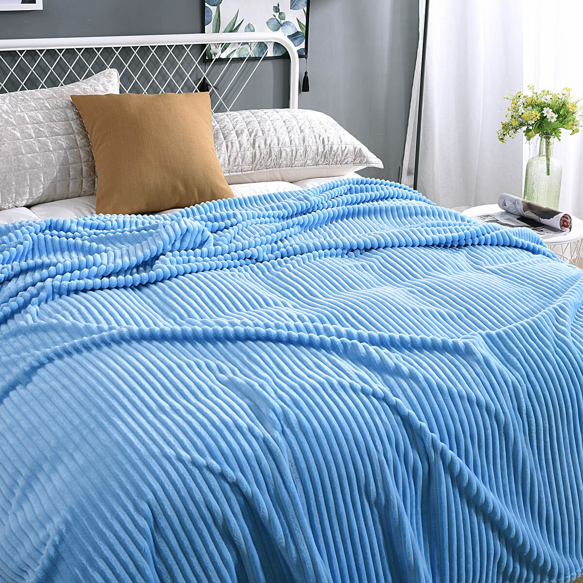 Lichtblauwe fluwelen fleece deken op een opgemaakt bed