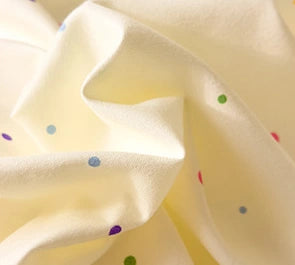 Detail van de crème stof met gekleurde confettistippen van CottonNest