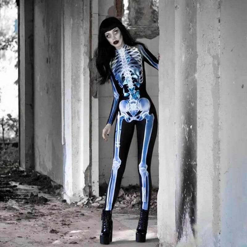 Vrouw heeft een 3D Halloween skeletoutfit aan met zwarte pruik en zwarte hoge schoenen aan staande in oude schuur