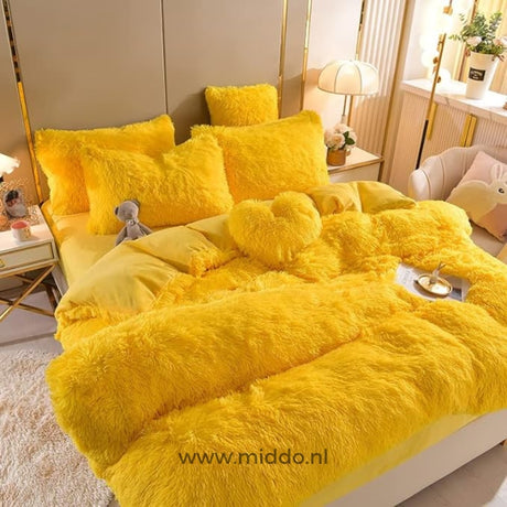 Geel 5 set fluffy fleece beddengoed met hartjes kussen netjes opgemaakt met klein berenknuffeltje op bed.