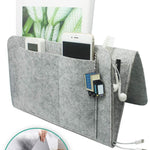 Lichtgrijze BedCaddy met erin een telefoon tijdschrift sleutelhanger kam en opening oplaadkabels.