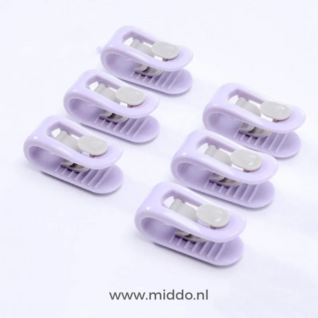 Zes paarse dekbedklemmen op witte achtergrond