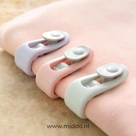 Drie dekbedklemmen in pastelkleuren op een deken