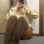 Model in bruine FluffSoks zittend op de vloer met telefoon