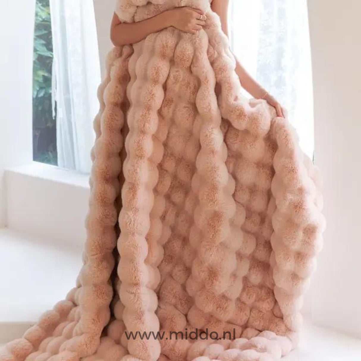 Vrouw gehuld in roze fluffy deken bij raam