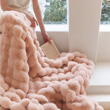 Roze fluffy deken over bank vrouw leest boek