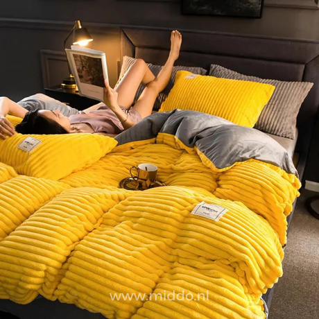 Vrouw ligt op bed met tijdschrift op geel dekbedovertrek