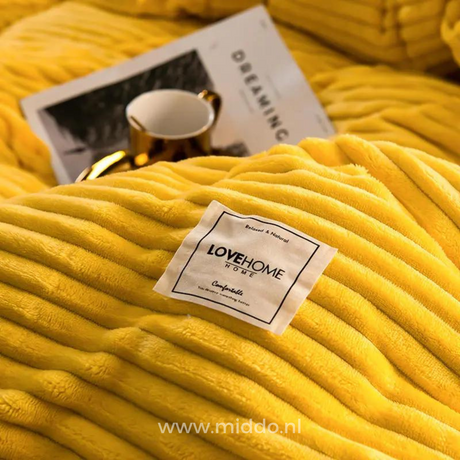 Close-up van geel dekbedovertrek met een kopje en tijdschrift