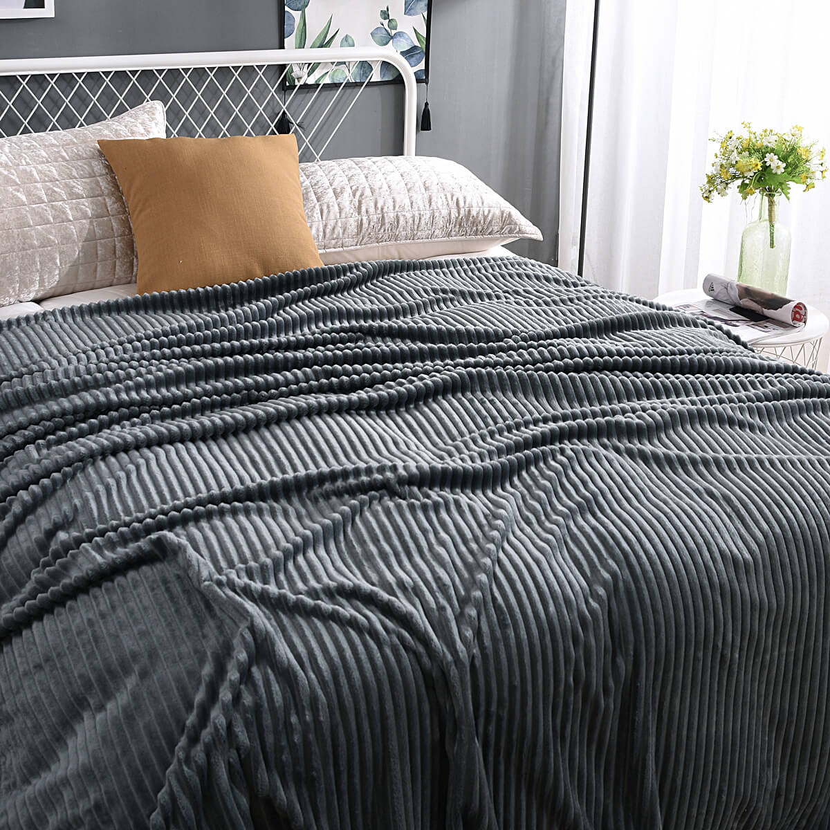 Donkergrijze fluwelen fleece deken op een opgemaakt bed