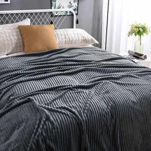 Donkergrijze fluwelen fleece deken op een opgemaakt bed