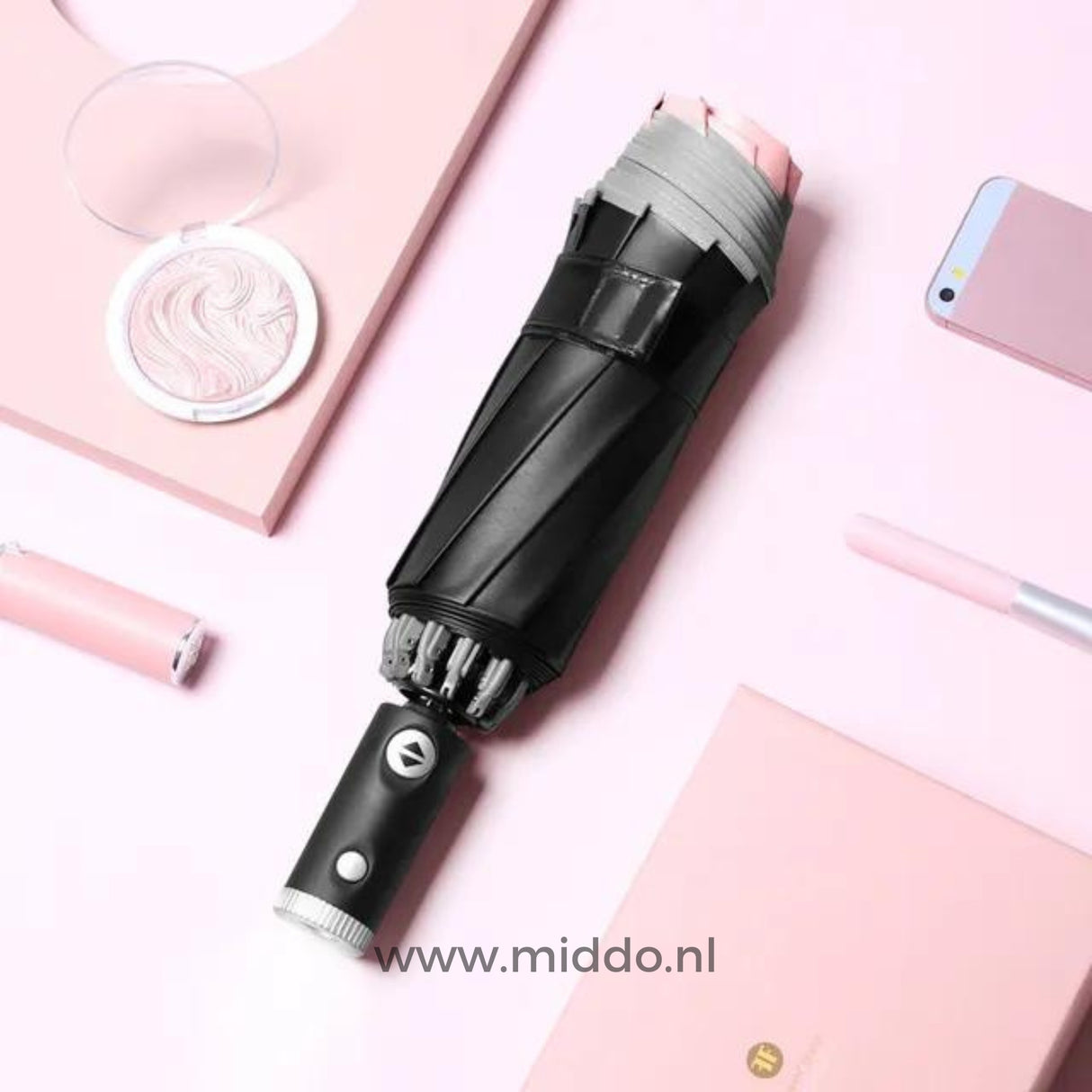 Zwarte paraplu met reflecterende rand met mobiel en pen op roze achtergrond.