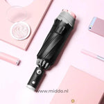 Zwarte paraplu met reflecterende rand met mobiel en pen op roze achtergrond.