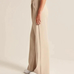 Vrouw met witte schoenen showt de wijde pantalon beige vanaf de zijkan