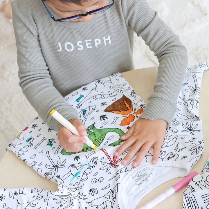 Jongen kleurt een inkleurbare dinosaurus pyjama in.