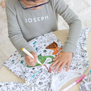 Jongen kleurt een inkleurbare dinosaurus pyjama in.