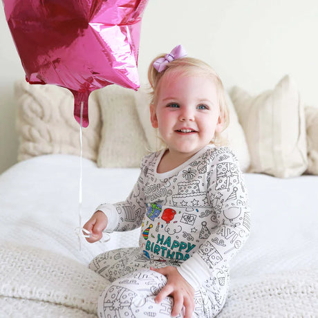 Meisje draagt een inkleurbare verjaardag pyjama met ballonnen.