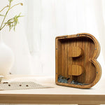 Houten spaarpot in de vorm van letter B gevuld met munten.