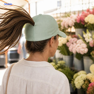 Vrouw met donkerbruin haar draagt een mintgroene Ponylite pet bij een bloemenmarkt