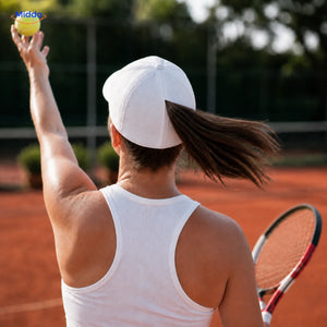 Vrouw met bruin haar draagt tijdens tennis een witte Ponylite pet met magnetische achternaad