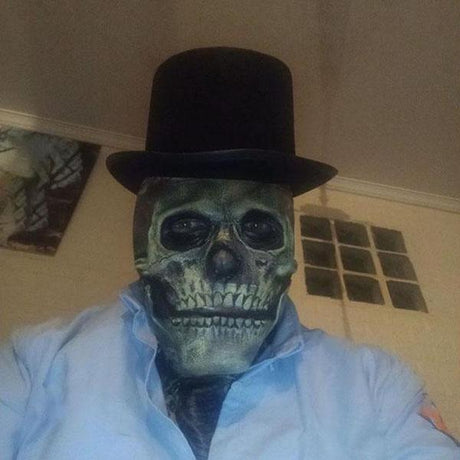 Persoon met realistisch schedelmasker en zwarte hoge hoed als griezelig Halloween kostuum
