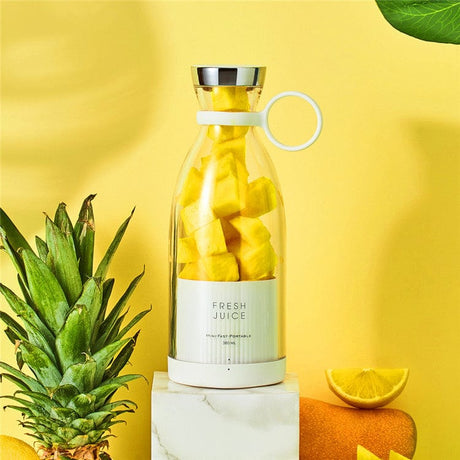Draadloze blender gevuld met ananas en omringd door fruit.