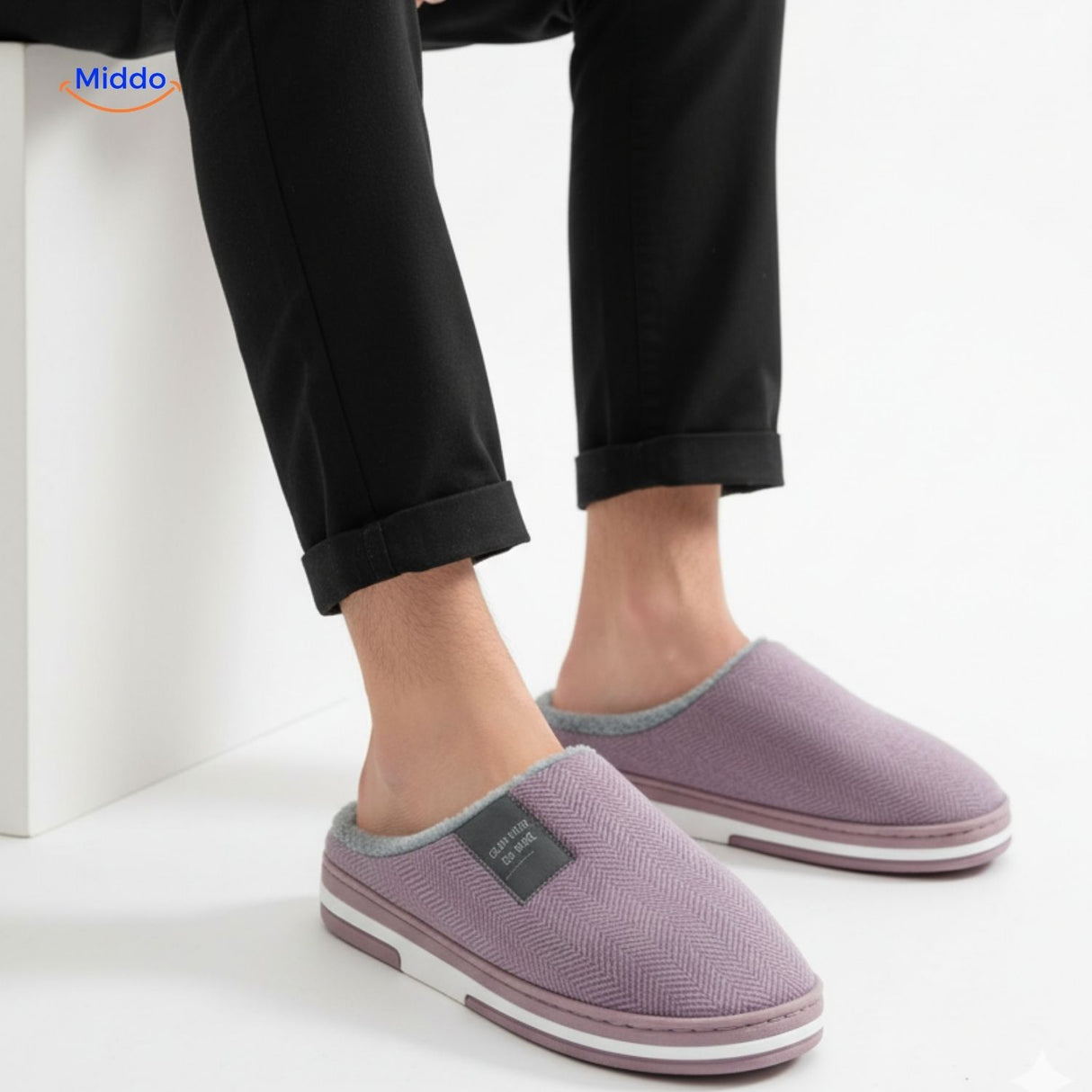warmtique pantoffels zacht katoen antislip en huiscomfort man zittend met lila pantoffels www.middo.nl